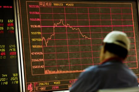 A man sits in front of a board showing market information at a securities brokerage house in Beijing