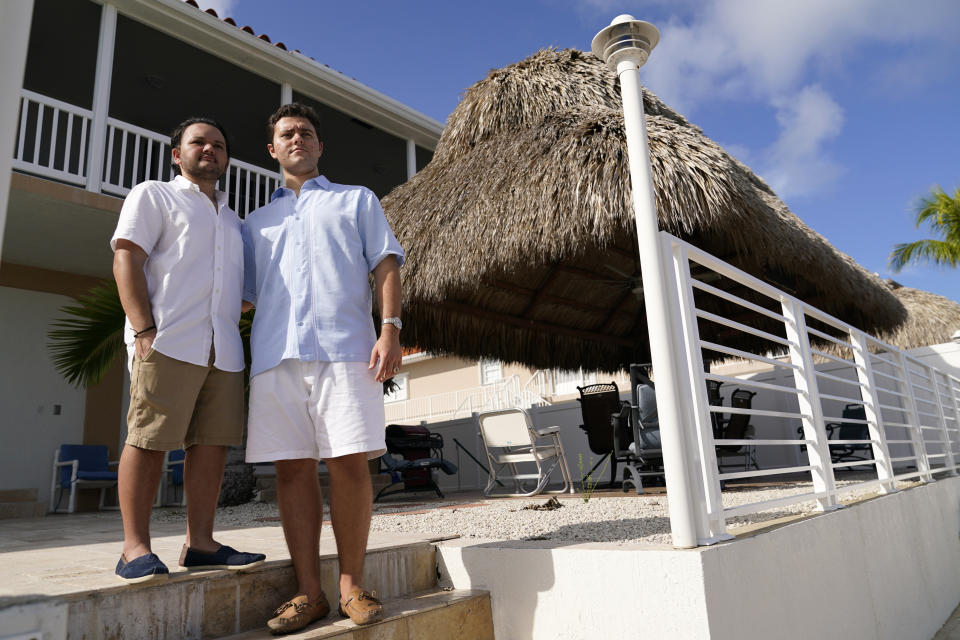 Freddy Vallejo Jr., right, poses for a photograph with his brother Joel, Saturday, Sept. 26, 2020, at the family vacation home in Key Largo, in the Florida Keys. Their grandfather Jorge Vallejo, a retired OB-GYN, and uncle Carlos Vallejo, who practiced internal medicine, died of the coronavirus within weeks of one another in South Florida. (AP Photo/Lynne Sladky)