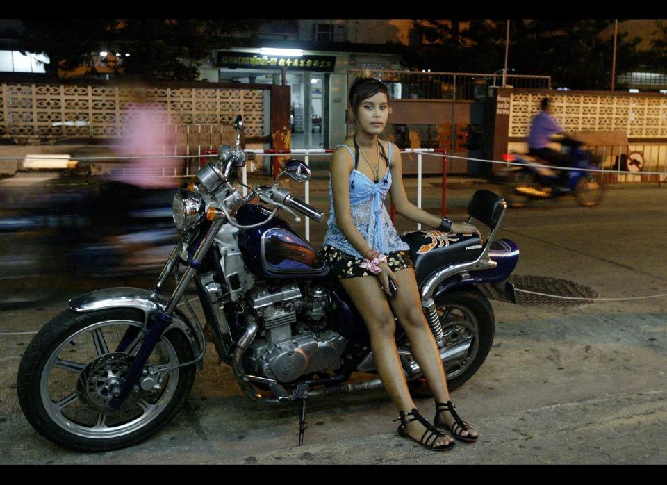 On Aug. 18, 2009, a bar girl waits for customers outside a bar in Sungai Kolok in Thailand's southern province of Narathiwat. The sun hasn't set, but already the music is pumping and the disco ball is rolling in the Sumtime Bar, where Malaysian men are enjoying the drinks and women available on this side of the Thai border. (Photo credit: Madaree Tohlala/AFP/Getty Images)