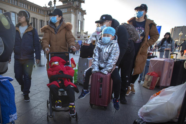 Travelers wear face masks as they walk outside of the Beijing Railway Station in Beijing, Monday, Jan. 20, 2020. China reported Monday a sharp rise in the number of people infected with a new coronavirus, including the first cases in the capital. The outbreak coincides with the country's busiest travel period, as millions board trains and planes for the Lunar New Year holidays. (AP Photo/Mark Schiefelbein)