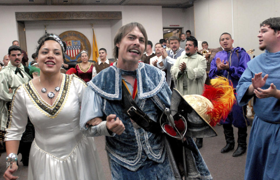 FILE - In this Sept. 5, 2006, file photo, Jessica Lucero, left, dressed as the Fiesta Queen, and Jaime Dean, right, dressed as 17th Century Spanish conquistador Don Diego de Vargas, dance and sing at Santa Fe City Hall in Santa Fe, N.M. In recent years, the conquistador and all the effigies connected to it have come under intense criticism from Native American activists who say the image glorifies indigenous genocide and needs to be removed from schools, streets and seals. (AP Photo/Jeff Geissler,File)