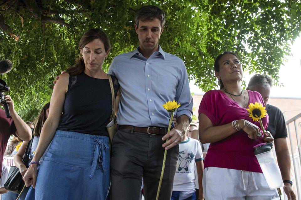 Democratic presidential candidate Beto O'Rourke walks next to his wife Amy Hoover Sanders and Rep. Veronica Escobar Sunday, Aug. 4, 2019, during a silent march holding sunflowers in honor to the victims of a mass shooting occurred in Walmart on Saturday, Aug. 3, 2019, in El Paso, Texas. (Lola Gomez/Austin American-Statesman via AP)