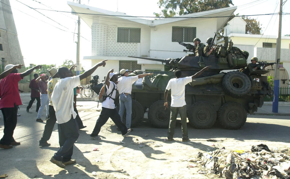 ARCHIVO - En esta fotografía del 7 de marzo de 2004, la gente le pide a la Armada de Estados Unidos intervenir durante un tiroteo que se desató en una marcha en Puerto Príncipe, Haití. (AP Foto/Pablo Aneli, Archivo)