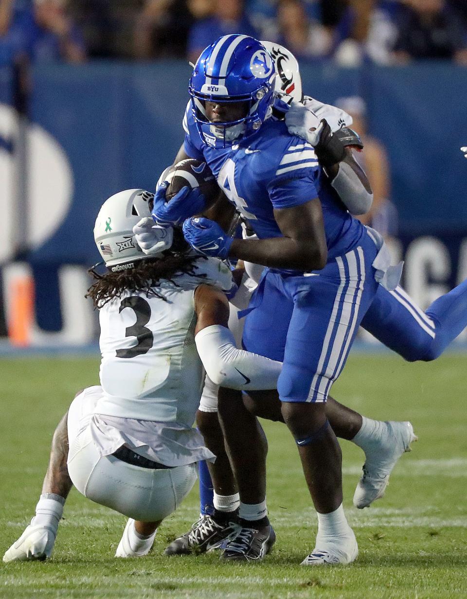 Brigham Young Cougars running back Miles Davis (4) gets tackled by Cincinnati Bearcats safety Deshawn Pace (3) and Cincinnati Bearcats defensive end Eric Phillips (97) during the second half of a football game at LaVell Edwards Stadium in Provo on Friday, Sept. 29, 2023. BYU won 35-27. | Kristin Murphy, Deseret News