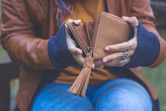 A woman holding open an empty wallet