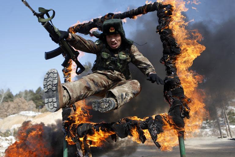 A soldier jumps through a ring of fire during a tactical training mission in Heihe, northeast China's Heilongjiang province, March 5, 2014