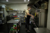 Rocio Sanchez works in the kitchen at La Francachela restaurant in Madrid, Spain, Friday, March 26, 2021. Experimenting with cutting back one workday per week is about to go nationwide in Spain. A 3-year pilot project will be using 50 million euros ($59 million) from the European Union's massive coronavirus recovery fund to compensate companies as they resize their workforce or reorganize production workflows to adapt to a 32-hour working week. (AP Photo/Manu Fernandez)