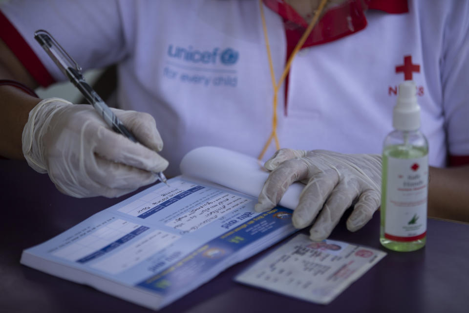 A Nepalese health worker notes down the information before inoculating a person against the coronavirus in Kathmandu, Nepal, Tuesday, June 8, 2021. Nepal resumed its stalled coronavirus vaccination campaign on Tuesday with 1 million doses given by China after the Himalayan nation made international pleas for help with a shortage of doses. (AP Photos/Bikram Rai)