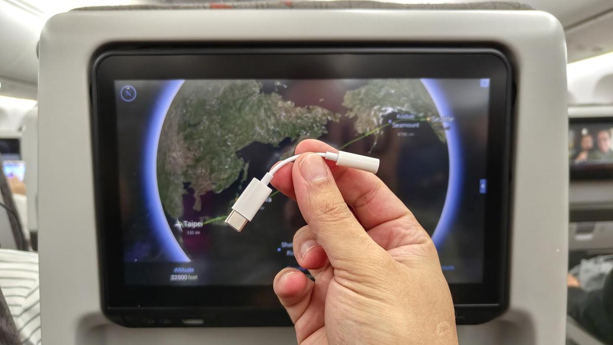  Apple's USB-C to 3.5mm headphone jack in front of a seat-back display on a plane. 