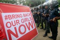 Supporters of the #BringBackOurGirls campaign hold a sign as police block supporters of the Chibok schoolgirls from marching to the president's official residence in Abuja on October 14, 2014