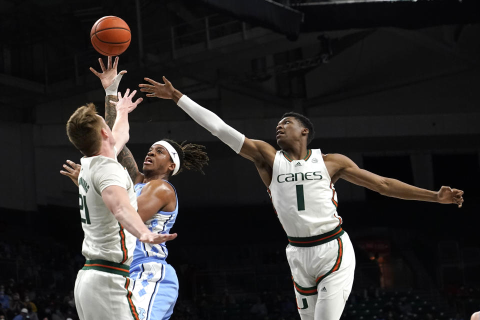 North Carolina forward Armando Bacot, center, goes to the basket as Miami forward Sam Waardenburg (21) and forward Anthony Walker (1) defend during the first half of an NCAA college basketball game, Tuesday, Jan. 18, 2022, in Coral Gables, Fla. (AP Photo/Lynne Sladky)