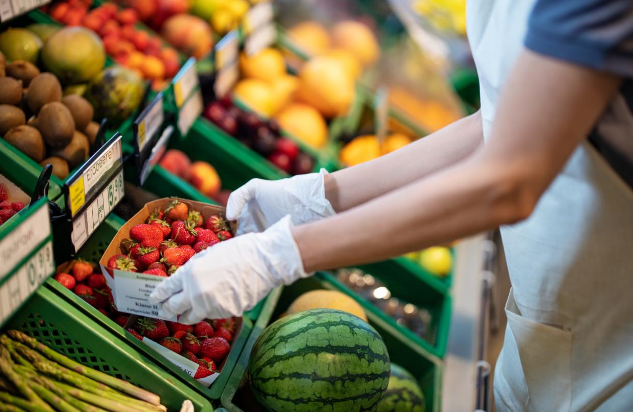 Grocer with strawberries, fruits, and vegetables.