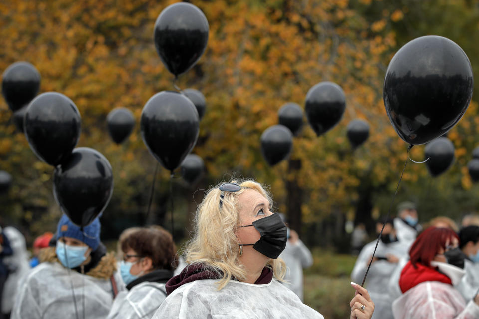 Medical workers, wearing masks for protection against the COVID-19 infection, hold black balloons in memory of those who lost their lives while in the care of the state health system in Bucharest, Romania, Tuesday, Nov. 17, 2020. A fire last week at a hospital treating COVID-19 patients in northeastern Romania killed 11 people who were intubated in the intensive care unit. (AP Photo/Vadim Ghirda)