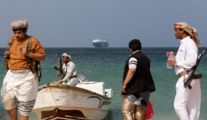FILE PHOTO: Armed men stand on the beach as the Galaxy Leader commercial ship, seized by Yemen's Houthis last month, is anchored off the coast of al-Salif