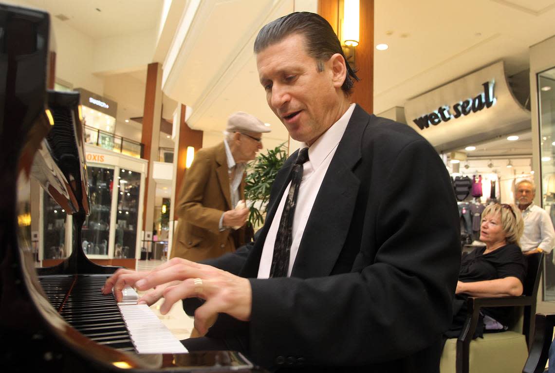 Gino Gaetano plays the piano at Aventura Mall on Tuesday evening, Oct. 5, 2010, as a listener dances in the background.