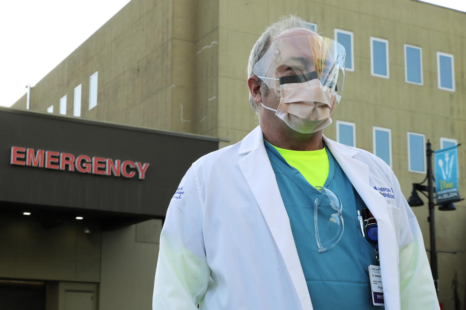 Dr. Stephen Anderson, a physician who works in the Emergency Department at the MultiCare Auburn Medical Center in Auburn, Wash., wears a mask and face shield as he poses for a photo before starting his shift, Tuesday, March 17, 2020, in Auburn, Wash., south of Seattle. Anderson said he writes messages on his shields to identify them as his, and this morning he chose the phrase "Stay Safe." “There just are not enough masks to go around at my hospital,” said Dr. Anderson. "I've got a two-day supply of masks so we're trying to be conservative. You get one in the morning. You clean it and reuse it." (AP Photo/Ted S. Warren)