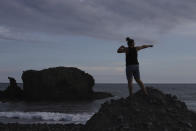 A tourist poses for a friend taking pictures along El Tunco Beach in Tamanique, El Salvador, Wednesday, June 9, 2021. In this beach community, a nongovernmental organization with the financial backing of an anonymous Bitcoin donor has been trying to create a small-scale cryptocurrency economy, and could serve as a showcase for the gains and struggles to introduce a phone-based cryptocurrency as the country embarks on a nationwide experiment after making Bitcoin legal tender this week. (AP Photo/Salvador Melendez)