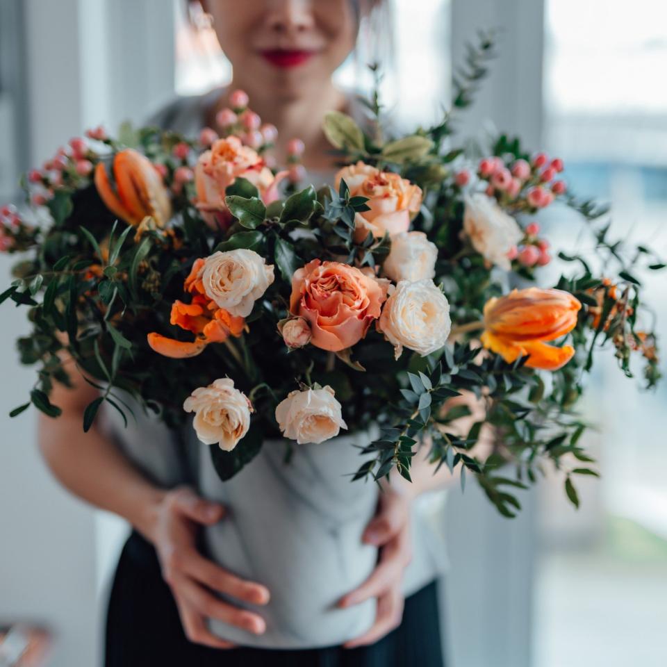 Shot of an unrecognisable woman covering her face with flowers in living room