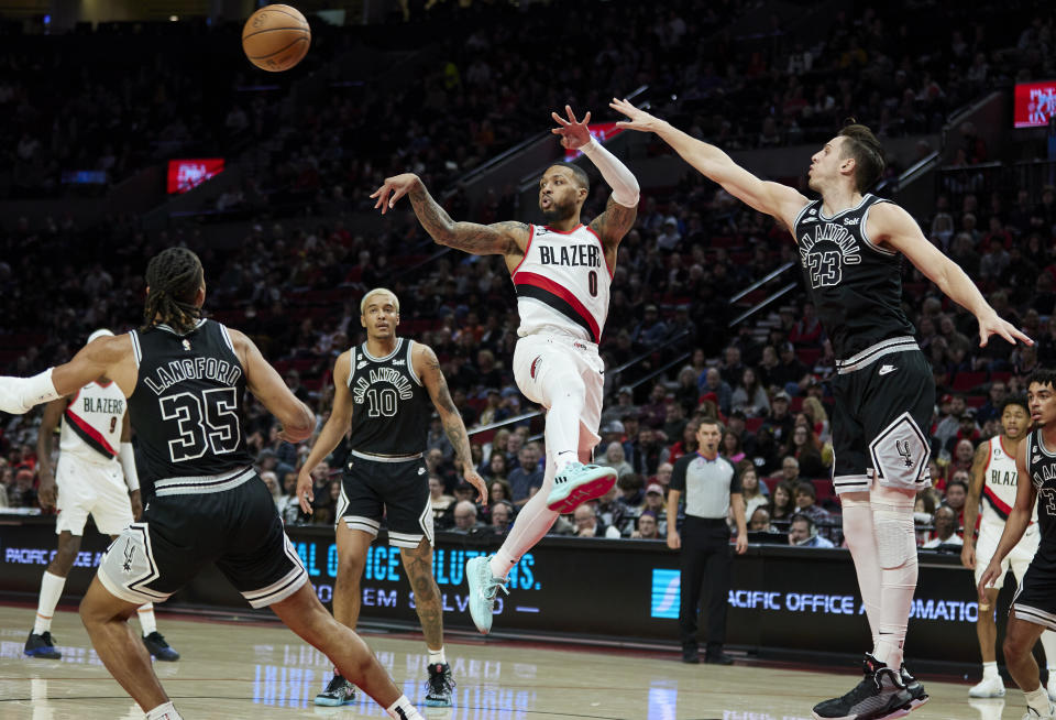 Portland Trail Blazers guard Damian Lillard (0) passes the ball away from San Antonio Spurs forward Zach Collins (23), guard Romeo Langford (35) and forward Jeremy Sochan (10) during the second half of an NBA basketball game in Portland, Ore., Monday, Jan. 23, 2023. (AP Photo/Craig Mitchelldyer)