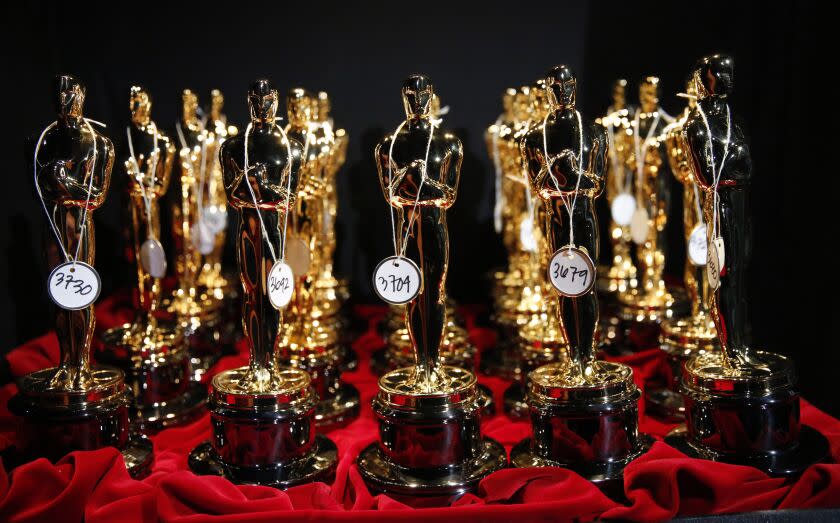A bunch of Oscars trophies positioned on a red table