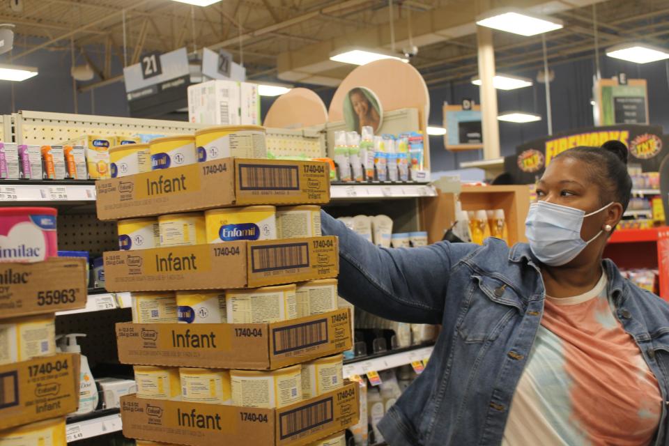 Benisha Wright picks up containers of infant formula that was about to be stocked on shelves at a Kroger store in Columbus, Ohio, on May 25, 2022. Two of her children rely on WIC for formula.