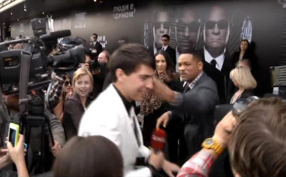 In this video image taken from AP video U.S. actor Will Smith, center right, slaps reporter Vitalii Sediuk, white suit, from the Ukrainian television channel 1+1 on the red carpet before the premiere of "Men in Black III" Friday May 18, 2012 in Moscow. Hollywood star Will Smith has slapped a male television reporter who tried to kiss him before the Moscow premiere of "Men in Black III." Smith pushed him away and then slapped him lightly across the cheek with the back of his left hand. (AP Photo via AP video)