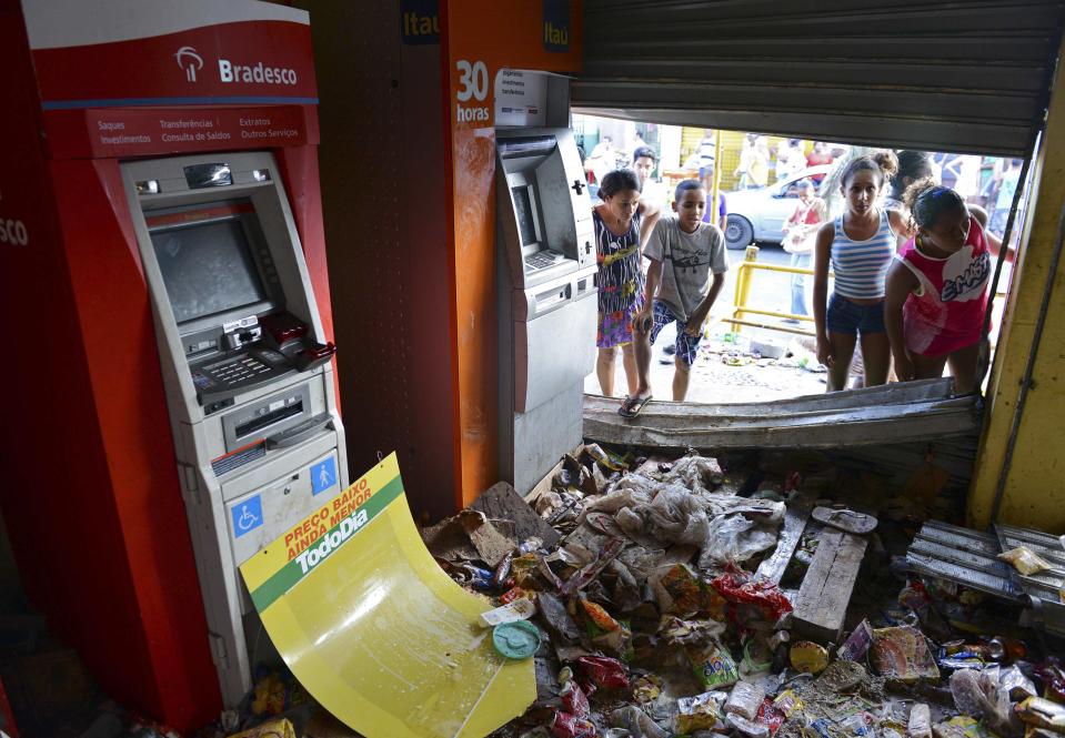 People look into a supermarket that was looted during a police strike in Salvador, Bahia state, April 17, 2014. A police strike has unleashed violent crime in Brazil's third-largest city just two months before it is set to welcome hordes of soccer fans for the World Cup, adding to fears about the country's ability to ensure safety during the event. At least 22 people were killed in and around the northeastern city of Salvador after state police went on strike early on Wednesday to demand better pay and other benefits, the Bahia state government said on Thursday, prompting the federal government to dispatch troops to restore order. REUTERS/Valter Pontes (BRAZIL - Tags: CRIME LAW POLITICS CIVIL UNREST SPORT SOCCER WORLD CUP)