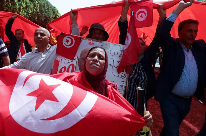 Supporters of Tunisian President Kais Saied carry flags and signs during a demonstration in Tunis
