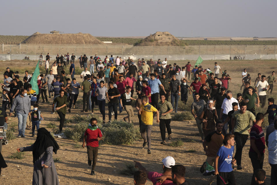 Palestinian protesters run to cover from teargas during clashes with Israeli troops, along the frontier with Israel, east of Gaza City, Monday, Aug. 21, 2023. Hundreds of Palestinians protested near the border fence with Israel. (AP Photo/Adel Hana)