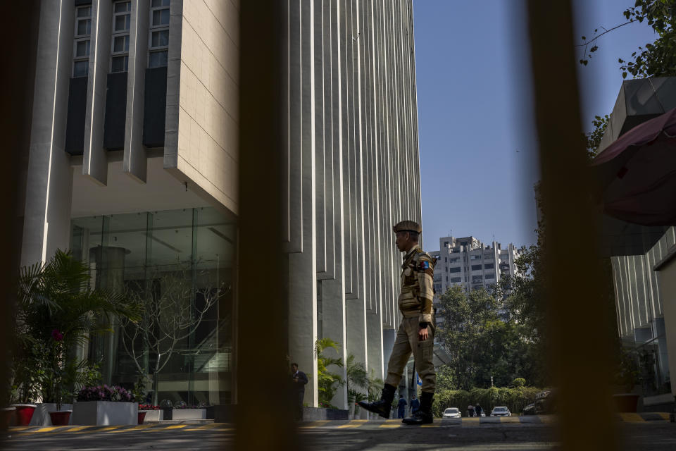 An armed security person stands stand guard at the gate of a building housing BBC office in New Delhi, India, Wednesday, Feb. 15, 2023. India’s tax officials searched BBC offices in India for a second straight day on Wednesday questioning the staff about the organization's business operations in the country, staff members said. (AP Photo/Altaf Qadri)