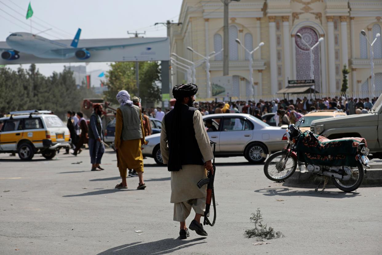 Taliban fighters stand guard in front of the Hamid Karzai International Airport in Kabul, Afghanistan on Monday, Aug. 16, 2021. Thousands of people packed into the Afghan capital's airport on Monday, rushing the tarmac and pushing onto planes in desperate attempts to flee the country after the Taliban overthrew the Western-backed government.