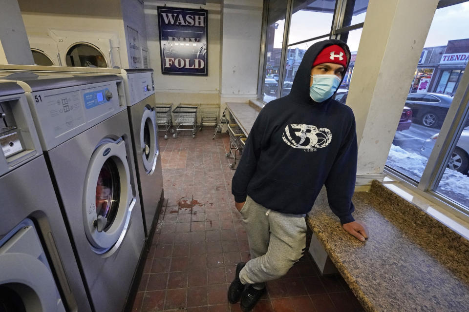 Cesar Osorio, a 30-year-old construction worker, waits for his clothes to dry at a laundromat in Chelsea, Mass., Feb. 10, 2021. Osorio said he and his family contracted the coronavirus last spring and recovered fairly quickly using home remedies like tea with honey. "If the government told me I must take the vaccine, then I'd take it, sure. But at the moment, I don't want it," he said. "Spanish people, we have our own medicines. We don't want vaccines." (AP Photo/Elise Amendola)