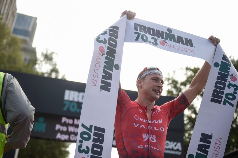 Jason West, first place triathlete for the pro men's group, holds the finish line ribbon after finishing the Ironman 70.3 at Augusta on Sunday, Sept. 25, 2022. West finished with a time of 3:35:18.