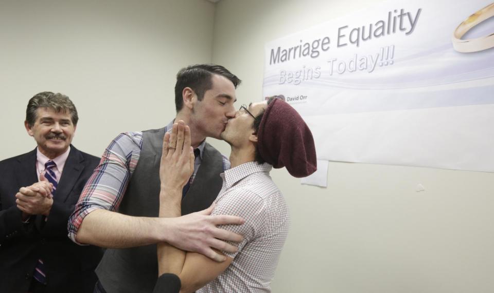 CORRECTS SPELLING TO WILK IN SECOND REFERENCE INSTEAD OF WILL - Charlie Gurion, center, and David Wilk kiss after obtaining their marriage license as Cook County Clerk David Orr, left,looks on Friday, Feb. 21, 2014, in Chicago. Same-sex couples in Illinois' largest county began receiving marriage licenses immediately after a federal judge's ruling Friday that some attorneys said could give county clerks statewide justification to also issue the documents right away. Illinois approved same-sex marriage last year; the new law takes effect June 1. However, U.S. District Judge Sharon Johnson Coleman ruled Friday that same-sex marriages can begin now in Cook County, where Chicago is located. Gurion and Wilk were the first couple to show up to get a license after the judge made her ruling. (AP Photo/M. Spencer Green)