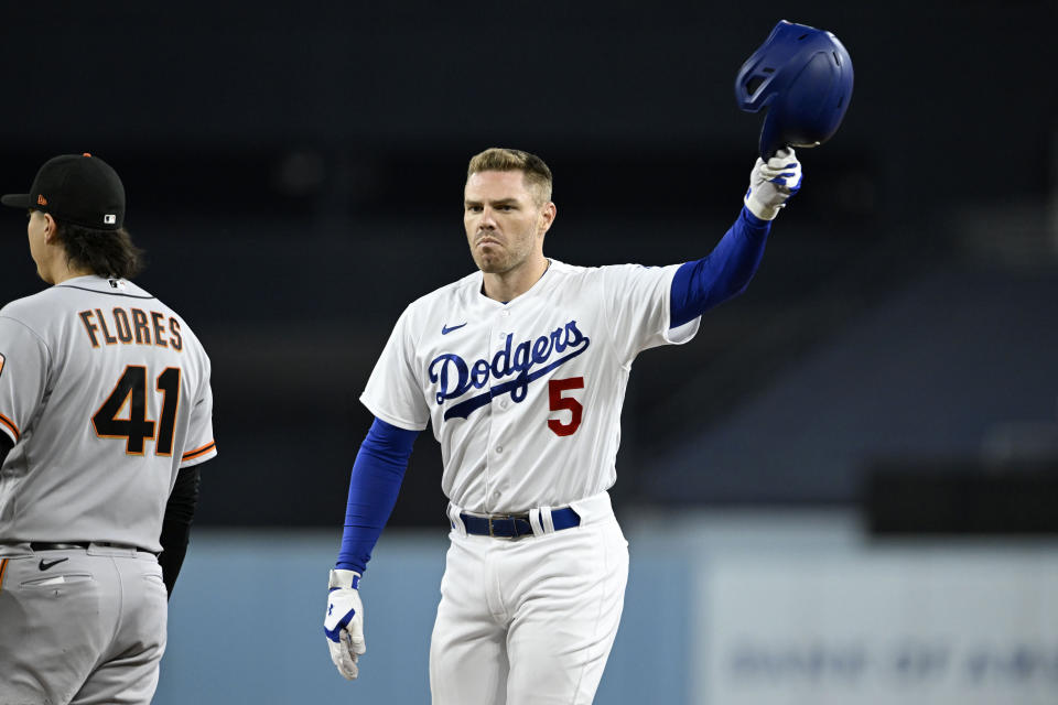 Los Angeles Dodgers' Freddie Freeman, right, acknowledges the fans after hitting his 200th hit for the season during the first inning of a baseball game against the San Francisco Giants in Los Angeles, Friday, Sept. 22, 2023. Giants first baseman Wilmer Flores, left, looks on. (AP Photo/Alex Gallardo)