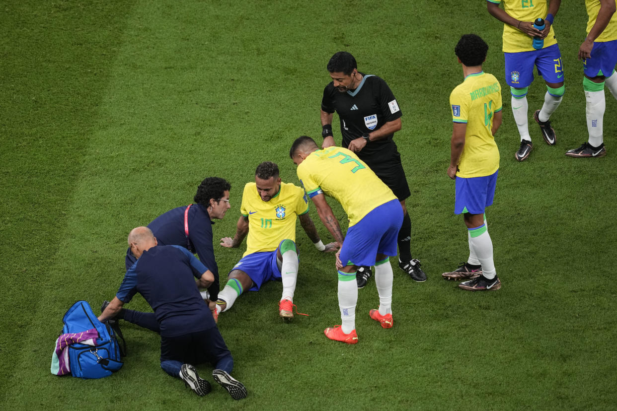 Brazil's Neymar, lies on the pitch as he receives first aid during the World Cup group G soccer match between Brazil and Serbia, at the the Lusail Stadium in Lusail, Qatar on Thursday, Nov. 24, 2022. (AP Photo/Darko Vojinovic)