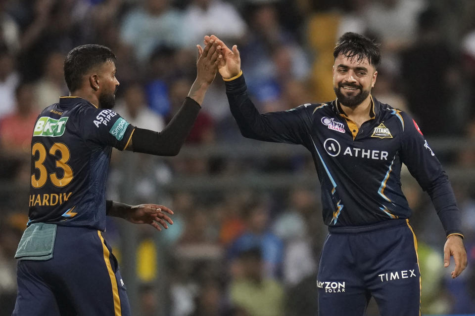 Gujrat Titans' Rashid Khan, right, celebrates with captain Hardik Pandya the wicket of Mumbai Indians' Tim David during the Indian Premier League cricket match between Mumbai Indians and Gujrat Titans in Mumbai, India, Friday, May 12, 2023. (AP Photo /Rajanish Kakade)