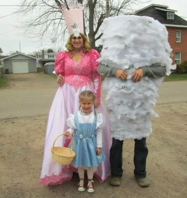 A little girl dressed as Dorothy, a man with feathers taped over his body to look like a tornado, and a woman in a pink princess outfit