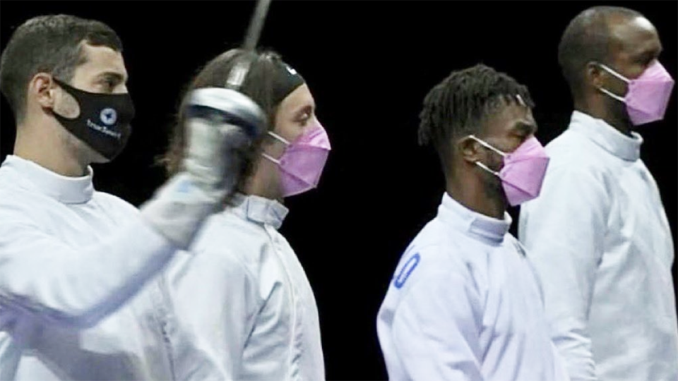 Three members of the USA fencing team wear pink masks in protest against teammate Alen Hadzic, wearing a black mask.