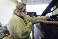 Courtney Crabtree check the temperature of a customer at a Witham Health Services drive-through Community Viral Screening center, Monday, March 16, 2020, in Whitestown, Ind. The screening center for coronavirus will help provide guidance and reduce unnecessary trips to the emergency room. (AP Photo/Darron Cummings)