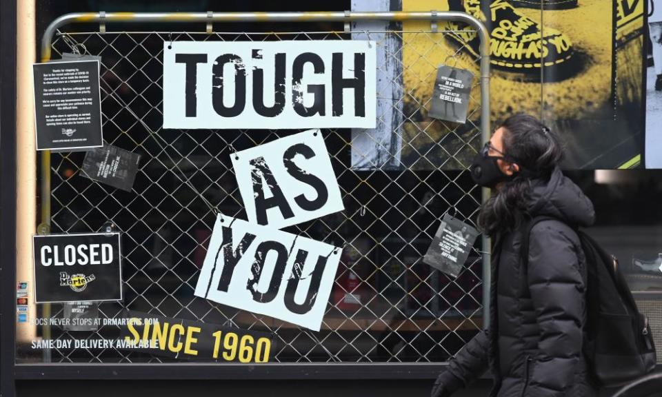 A person with a face mask walks by a Dr Martens store in New York City