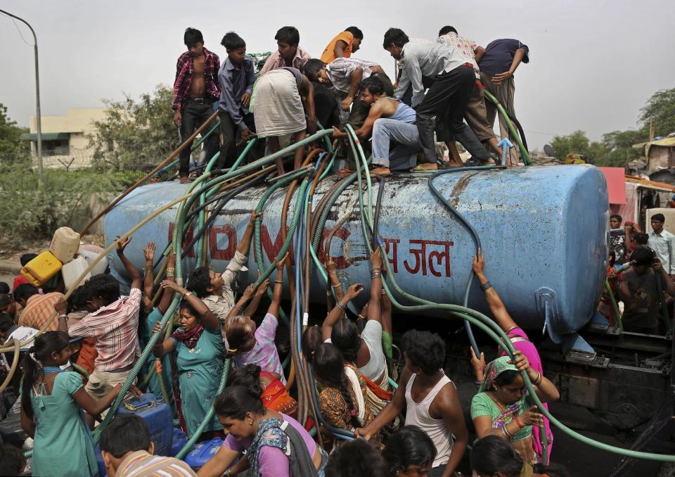 FILE - In this July 6, 2012 file photo, residents crowd around a government tanker delivering drinking water because of short supply in running water taps in New Delhi, India. As India faces certain water scarcity and ecological decline, the country’s main political parties campaigning for elections have all but ignored environmental issues seen as crucial to India’s vast rural majority, policy analysts say. (AP Photo/Kevin Frayer, File)