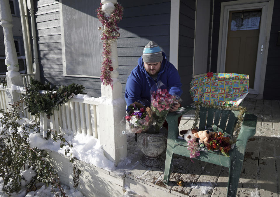 Neighbor Eric Stiver put flowers and stuffed animals on a chair on the porch of the home where a deadly shooting occurred in Minneapolis on Monday, Dec. 2, 2019. Police in Minneapolis haven’t yet identified the people who died. (Brian Peterson/Star Tribune via AP)