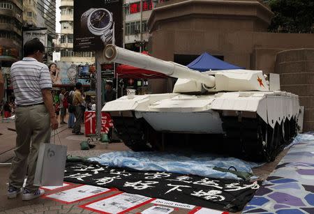 A shopper stands in front of a mock tank made by university students, imitating those used during the military crackdown on the pro-democracy movement at Beijing's Tiananmen Square in 1989, during an exhibition on the movement at Hong Kong's Causeway Bay shopping district June 3, 2014. Wednesday marks the 25th anniversary of the crackdown. REUTERS/Bobby Yip