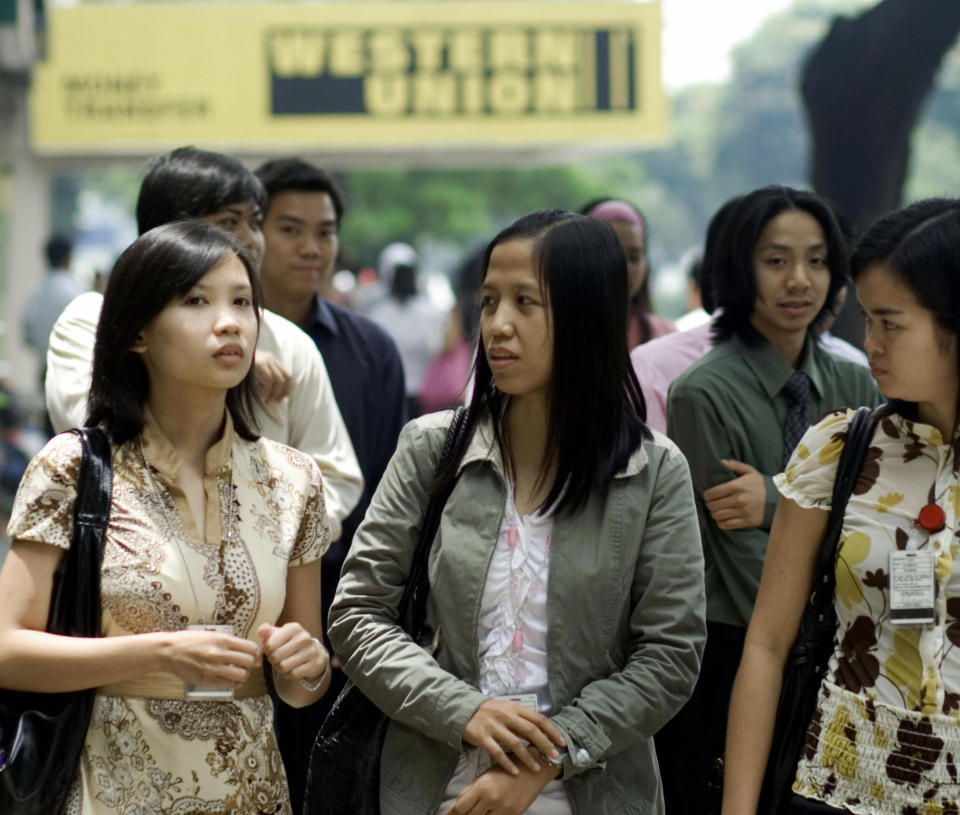 File Photo: Office employees walk past a logo of remittance bank Western Union at the financial district of Manila. (Photo: DIANA PRADO/AFP via Getty Images)