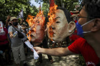 Activists burn masks of Ferdinand "Bongbong" Marcos Jr. and running mate Sara Duterte, daughter of the current president, during a rally at the Commission on Human Rights in Quezon City, metro Manila, Philippines on Wednesday. May 25, 2022. Marcos Jr. continues to lead in the official canvassing of votes. (AP Photo/Basilio Sepe)