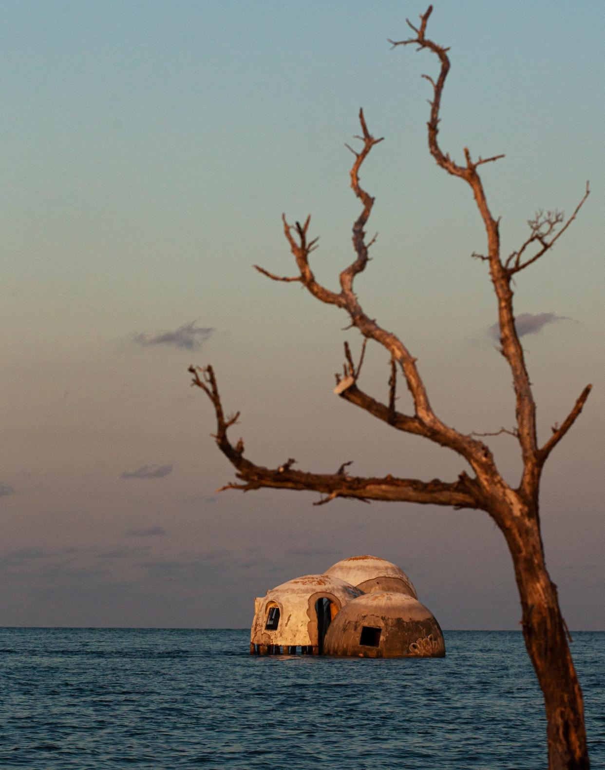 Waves lap on the sides of the dome homes on Cape Romano in Collier County, Florida, in late June 2022. The homes were built on the beach on dry land in the early 1980s. Without ever moving, they now find themselves several hundred feet offshore. Erosion, hurricanes and strong tropical weather have contributed to the demise of the homes. Climate change is causing sea-level rise. Planners say that the homes should have never been built in this location due the changing landscape of barrier islands.