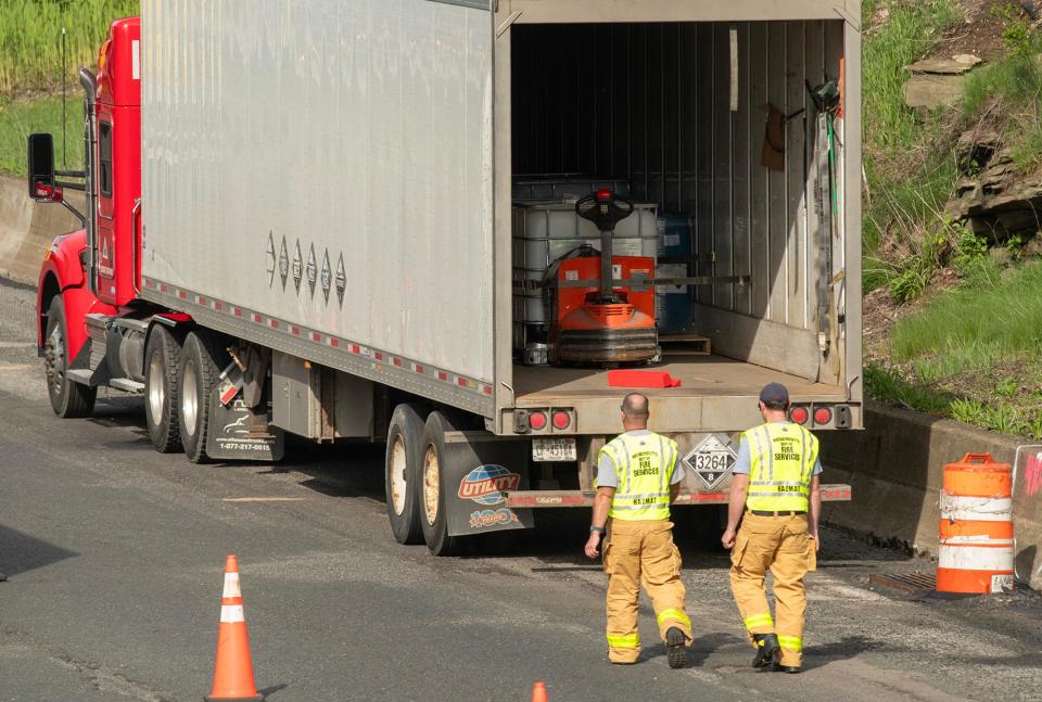 Hazardous materials responders examine the leaking cargo inside a tractor-trailer on the side of the Mass Pike eastbound Monday afternoon. Traffic is backed up for miles in both directions.
