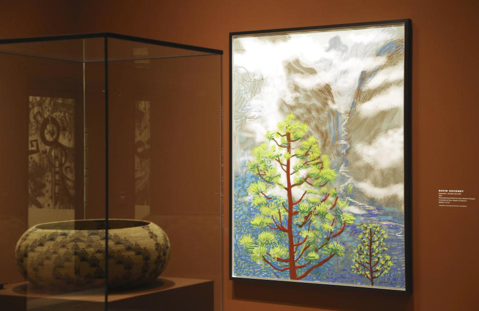 In this Wednesday, Oct. 23, 2019 photo, British artist David Hockney's Yosemite artistic work, right, along with baskets from weavers of the Miwok and Mono Lake Paiute tribes are on display at the Heard Museum, in Phoenix. "David Hockney's Yosemite and Masters of California Basketry" exhibition opens Monday. (AP Photo/Ross D. Franklin)