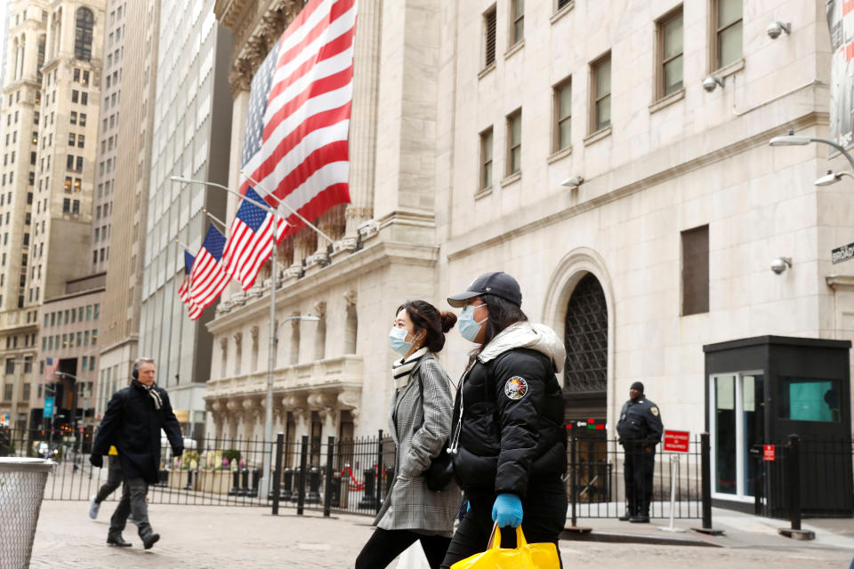 People wearing a protective mask walk in front of the New York Stock Exchange (NYSE) shortly as coronavirus disease (COVID-19) cases rise in New York City, U.S., March 16, 2020. REUTERS/Lucas Jackson